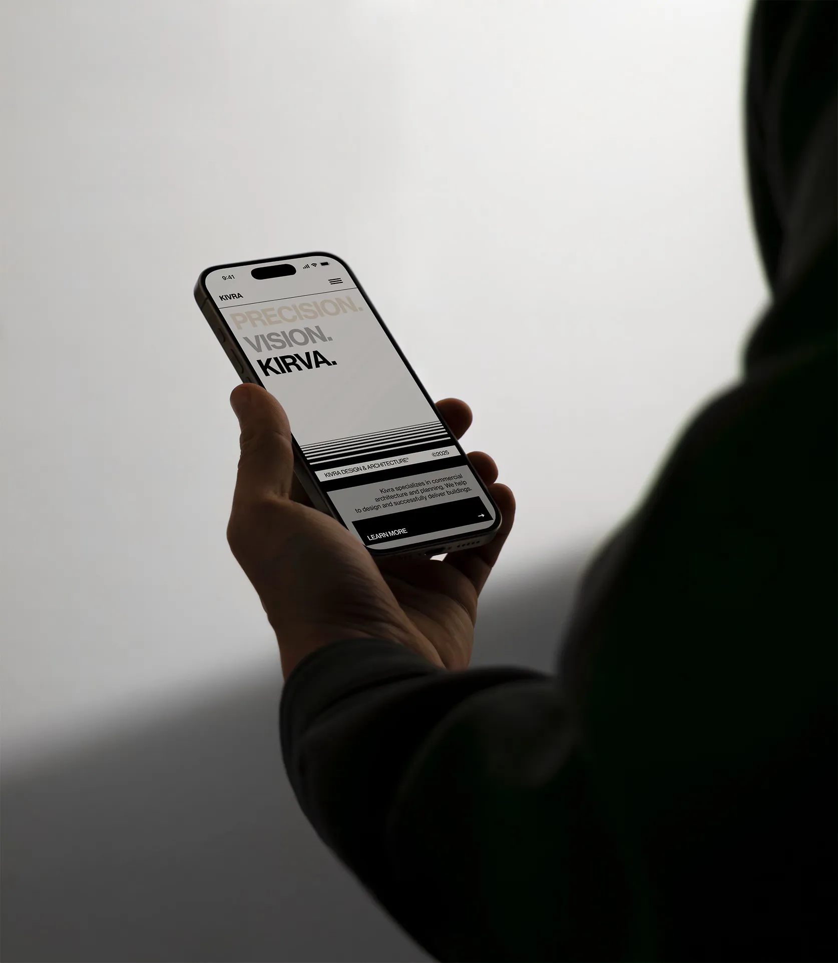 Hand holding a smartphone displaying a website with text 'PRECISION. VISION. KIVRA.' and a 'Learn More' button.