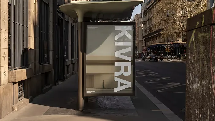 Bus stop shelter on a city sidewalk with a vertical advertisement reading 'KIVRA' in large white letters.