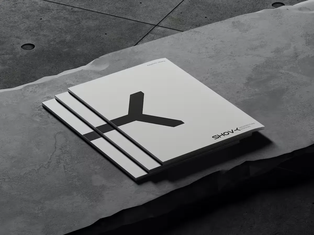 Stack of three grey architectural design journals with a minimalist black Y-shaped design on the cover, placed on a textured stone surface.